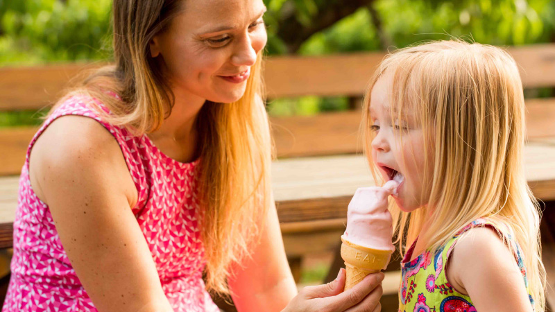mother feeding ice cream to daughter