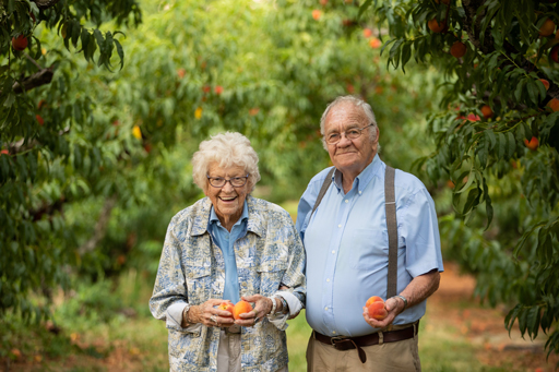 Ruth and Henry Chiles holding peaches in the orchard