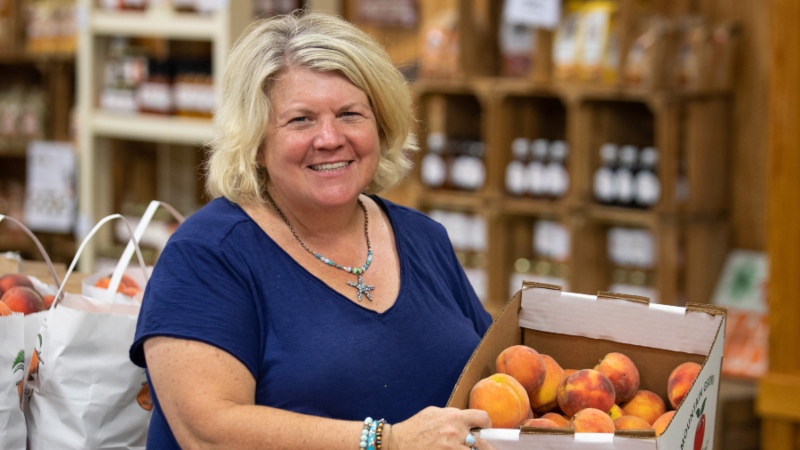 Cynthia Chiles holding a box of peaches at Chiles Peach Orchard